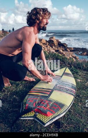 Giovane uomo che pulisce surf board Foto Stock