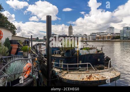 Houseboats si oppone all'architettura di gentrifificazione lungo il fiume Tamigi a Battersea, Greater London, England, United Kingdom, Europe Foto Stock