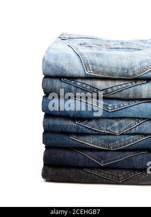 Lotto di jeans usati accatastati in un palo isolato sopra bianco Foto Stock