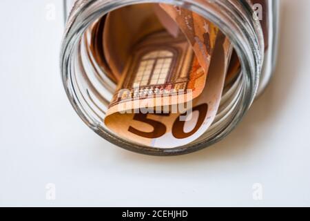 Composizione con banconote di risparmio (50 EURO) in un vaso di vetro. Concetto di investimento e di mantenimento del denaro, primo piano isolato. Foto Stock