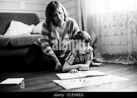 La madre è impegnata nella formazione del figlio giovane. Fotografia in bianco e nero. Foto Stock