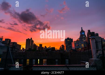 Il cielo sopra gli edifici dell'East Village, che si illumina al tramonto Foto Stock