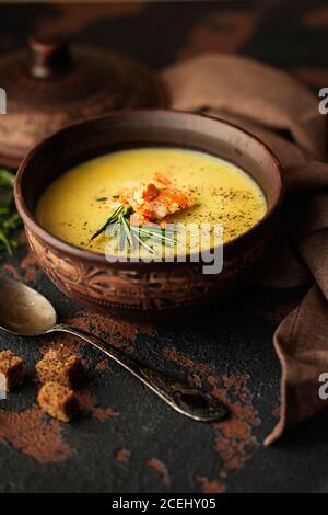 Zuppa di crema di pesce con salmone, formaggio, patate ed erbe in ciotola di zuppa di ceramica marrone. Fotografia di cibo scuro Foto Stock