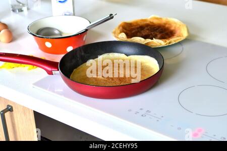 Cottura di frittelle dolci sottili in una padella su un fornello elettrico, Shrovetide Foto Stock