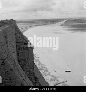 Francia, anni '50, vista storica di le Mont-Saint-Michel, Normandia, un'isola marea e comune che mostra un angolo dell'antica fortezza. L'isola si trova al largo della costa nord-occidentale della Francia, alla foce del fiume Couesnon. St Michael's Mount in Cornovaglia, Regno Unito, è simile a Mont-Michel. Foto Stock