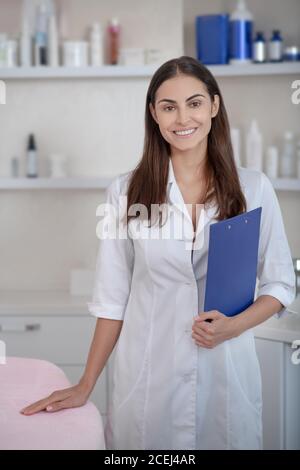 Abbastanza giovane professionista in piedi nella stanza e sorridente Foto Stock