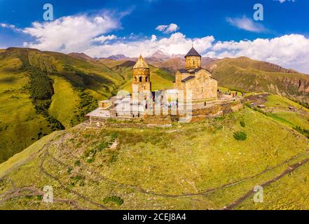 Bella vista dall'alto dal drone a Tsminda Sameba o Chiesa della Santissima Trinità vicino al Villaggio di Gergeti in Georgia e dell'alta montagna Kazbek, Caucaso Foto Stock