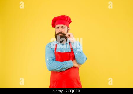 Ottimo cibo. Hipster maturo con viso serio. Cuoco saziato. Macellaio brutale in grembiule. Migliore offerta di menu. Confidente cuoco in uniforme rossa. Chef maschile in uniforme rossa. Foto Stock