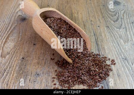 versamenti di semi di lino dal cucchiaio di legno, su un tavolo di legno Foto Stock