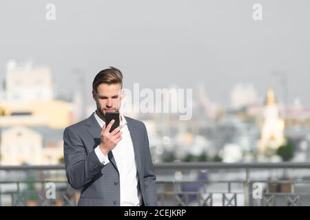 Imprenditore faccia gravi ricevuto messaggio importante, skyline background. Il concetto di messaggio. Uomo in tuta imprenditore assume i vantaggi delle moderne tecnologie mobili. Uomo legge il messaggio telefono mobile. Foto Stock