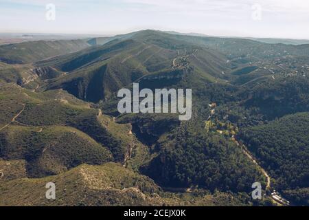 Pittoresca vista sul drone di un incredibile terreno collinare coperto di erba verde e alberi a Cuenca, Spagna Foto Stock
