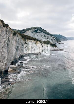 Ondulazione del mare nei pressi di colline verdi Foto Stock