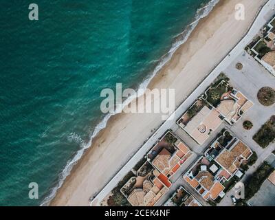 Spettacolare vista sul drone di un mare blu che ondeggiante vicino alla sabbia spiaggia e piccola città costiera Foto Stock