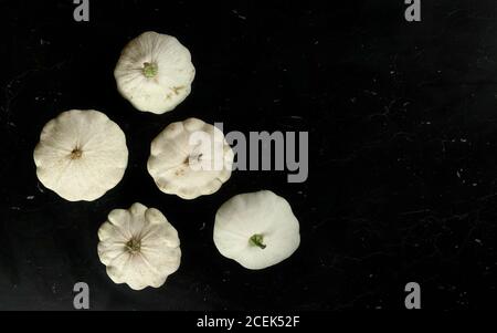 Vista dall'alto verso il basso, cinque squadretti di pattypan bianchi su marmo scuro come il tabellone, spazio per il testo a destra Foto Stock