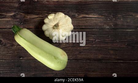 Vista dall'alto in basso, zucca e zucchine di pattumiera su tavola di legno scuro, ampio striscione, spazio per il testo sul lato destro Foto Stock