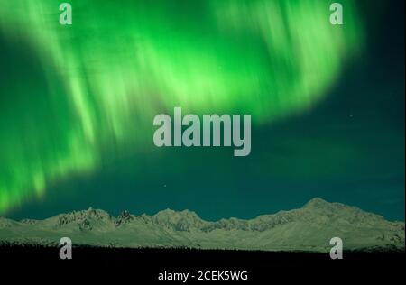 Alaska Range Mountains, illuminato con l'aurora boreale o l'aurora boreale nel cielo invernale. Mt. Denali (r); Mt Hunter (l) sotto la luna piena. Foto Stock
