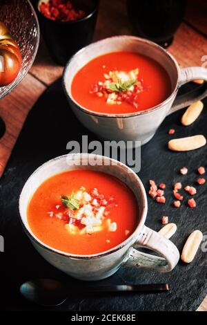 Gazpacho di pomodoro servito con uova e prosciutto in tazze Foto Stock