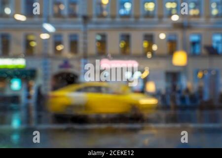 Serata di pioggia offuscata astratta . Primo piano di taxi giallo fermo. Ambiente urbano moderno Foto Stock