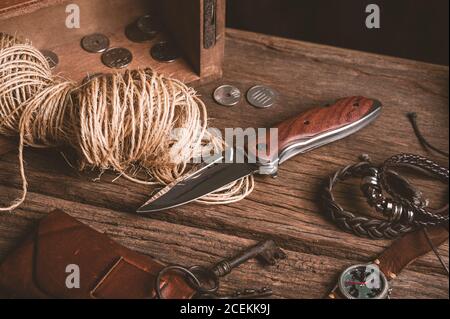 Coltello pieghevole in acciaio inox con manico in legno e altri articoli per il trasporto quotidiano (EDC) per uomo. Primo piano sul coltello pieghevole. Foto Stock