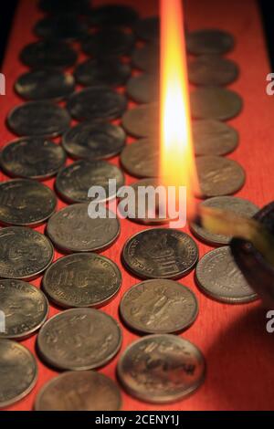 Monete di rupia indiane con luce a candela. Pila di monete da 1, 2, 5, 10 rupie indiane in metallo isolato su sfondo rosso. Finanziario, economia Foto Stock