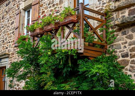 Tradizionale architettura in pietra casa nel villaggio francese. Finestra balcone giardino decorato con un mix di molte piante e fiori in pentole di legno. Foto Stock
