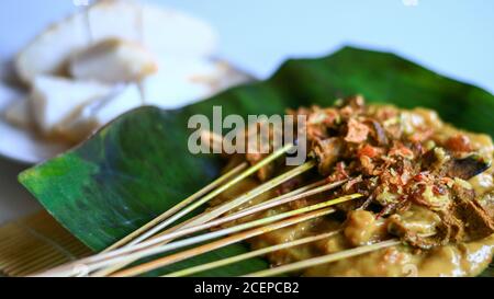 Sate Padang o Padang Satay e ketupat (torta di riso tradizionale) su foglia di banana. Foto Stock