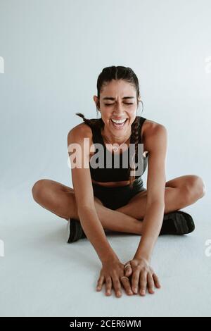 Donna sana rilassarsi dopo una sessione di allenamento. Donna allegra di forma fisica seduta su sfondo bianco. Foto Stock