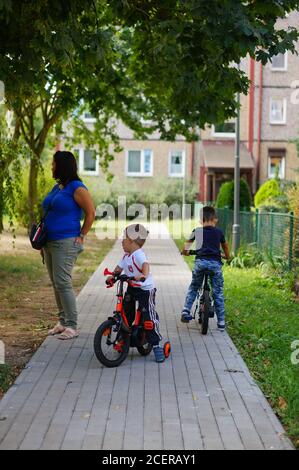 POZNAN, POLONIA - 30 agosto 2020: Donna e due ragazzi in bicicletta su un sentiero in un parco Foto Stock