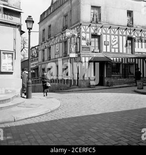 1950s, storico, Parigi, Francia, strada acciottolata ed edifici nella zona di Montmartre della città parigina, famosa per i suoi artisti di strada e la chiesa, Sacre Coeur. La foto mostra l'angolo di Rue des Saules e Rue Saint-Ristique - la strada Oldes a Montmarte - e il ristorante, 'Entree des Jardins'. Foto Stock