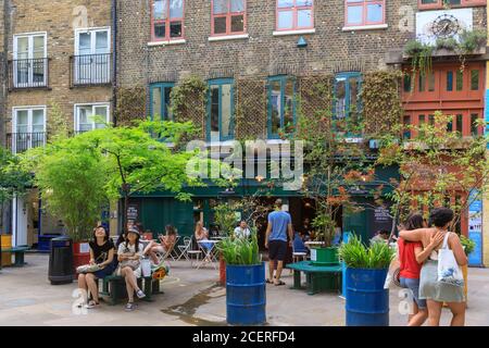 Persone a Neil's Yard, caffè all'aperto e pop up in trendy cibo urbano salute e destinazione di vita alternativa a Covent Garden, Londra, Inghilterra, Regno Unito Foto Stock