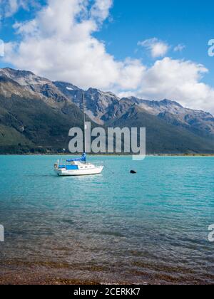 Uno yacht ormeggiato sulle acque blu del lago Wakatipu Circondato da montagne a Glenorchy Nuova Zelanda Foto Stock