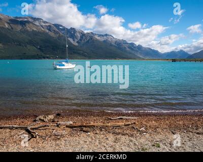 Uno yacht ormeggiato sulle acque blu del lago Wakatipu Circondato da montagne a Glenorchy Nuova Zelanda Foto Stock