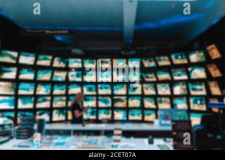 Il concetto di videosorveglianza. Ufficio con un dipendente sullo sfondo di molti monitor collegati a telecamere TVCC. Sfocatura. Foto Stock