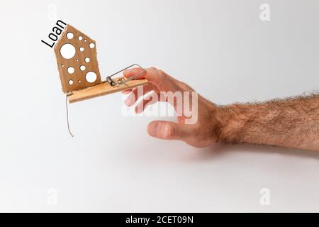 Concetto di investimenti e rischi bancari. La mano di un uomo cade in un mousetrap, con un inserto di cartone sotto forma di formaggio. Prestito di testo. Foto Stock