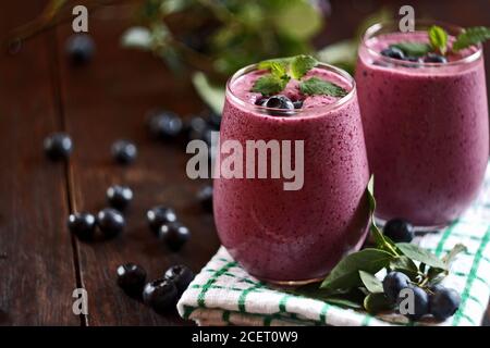 Due bicchieri di frullato di mirtillo su sfondo di legno. Messa a fuoco selettiva Foto Stock