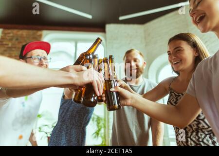 Bottiglie per la graffatura. Gruppo giovane di amici che beve birra, divertendosi, ridendo e festeggiando insieme. Donne e uomini con bicchieri di birra. Oktoberfest, amicizia, togetherness, concetto di felicità. Foto Stock