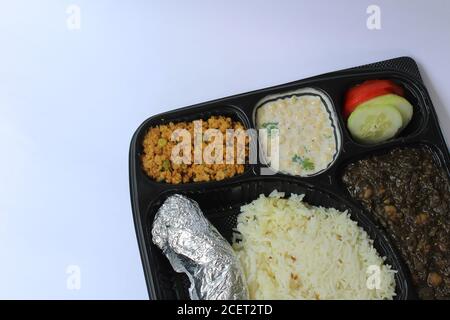 Delizioso cibo vegetariano indiano in un piatto di plastica su un sfondo bianco Foto Stock