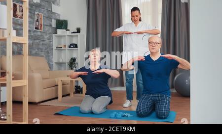 Coppia anziana che fa la terapia fisica con il medico a casa. Assistenza domiciliare, fisioterapia, stile di vita sano per anziani, allenamento e stile di vita sano Foto Stock