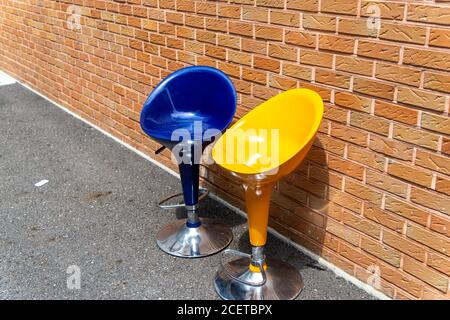 Ci sono due sedie di plastica scartate nel parcheggio della casa. È un sedile per fumatori, ma nessuno è qui a causa del calore e del non-face-t Foto Stock