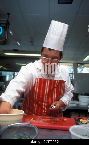 Giovane uomo con difficoltà di apprendimento lavorando come chef UK Foto Stock