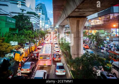 Guardando giù sulla congestionata Sukhumvit Rd vicino al raccordo di Asoke al crepuscolo. Ripresa da un percorso sopraelevato che attraversa la strada. Bangkok Thailandia. Foto Stock