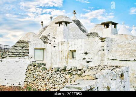 Gruppo di bellissimi Trulli bianchi, tradizionali capanne in pietra a secco pugliesi vecchie case con tetto conico in Valle d'Itria, Puglia, Italia Foto Stock