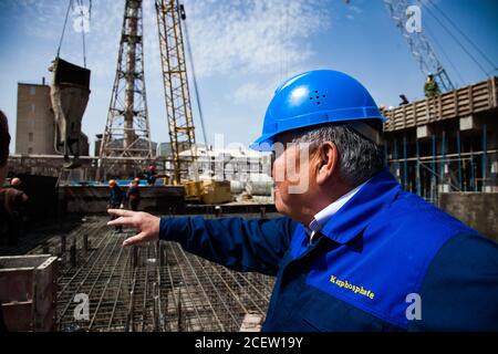 Vecchio impianto di fertilizzante fosfato in modernizzazione. Costruzione di un nuovo edificio industriale. Ingegnere in casco blu e abbigliamento da lavoro. Rinforzo in acciaio Foto Stock