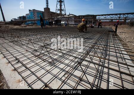 Vecchio impianto di fertilizzante fosfato in modernizzazione. Costruzione di nuovi edifici industriali. Lavoratori che assemblano rinforzi in acciaio del seminterrato dell'edificio Foto Stock