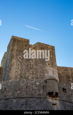 Fortezza dall'esterno, cielo azzurro chiaro giornata di sole con moto d'aereo in aria. Scenario vista invernale della città vecchia mediterranea di Dubrovnik, famoso viaggio europeo e destinazione storica, Croazia Foto Stock