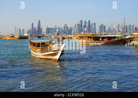 DOHA, QATAR -12 DEC 2019- Vista al tramonto del moderno skyline di Doha con le tradizionali barche in legno dhow di fronte. La capitale del Qatar include molti super Foto Stock