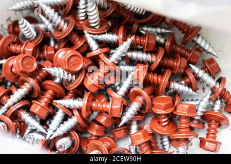 Pila di viti rosse per tetti in un negozio di ferramenta Foto Stock