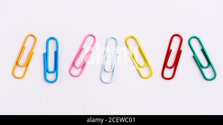 Clip di carta color pastello isolate su sfondo bianco. Graffette in plastica rossa, rosa, gialla, blu e verde. Ufficio d'affari e cancelleria scolastica Foto Stock