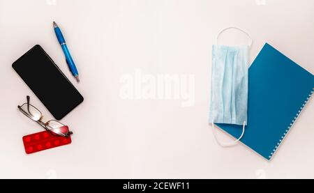 Rimani a casa bianco sfondo flatlay. Home Office smartphone dizionario medico maschera compresse pillole strisce lungo banner Foto Stock