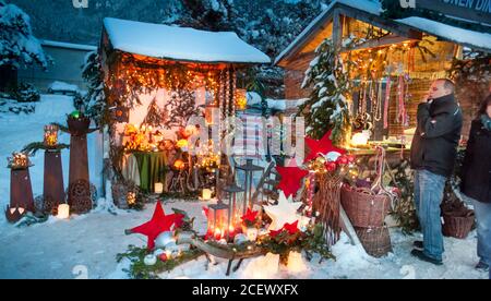 Ettal, Germania/Baviera – 31 dicembre 2019: Mercatino di Natale innevato con negozi illuminati in capanne di legno con regali e decorazioni fatte a mano. Foto Stock